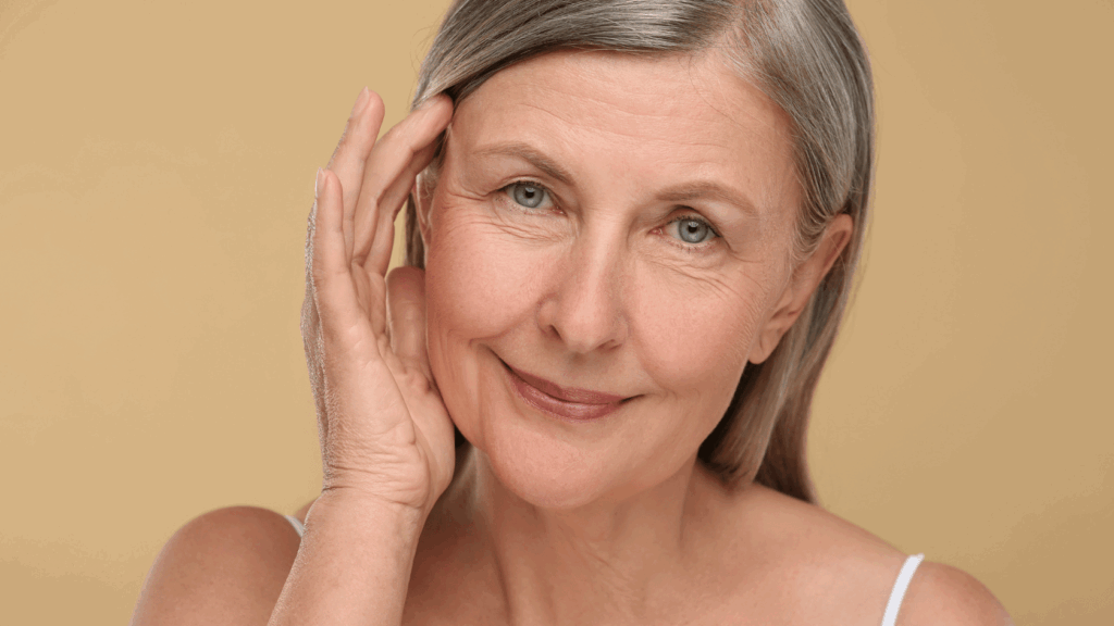 Donna matura con capelli grigi e pelle curata, tocca delicatamente il viso, simbolo di benessere e medicina anti-aging a Milano.