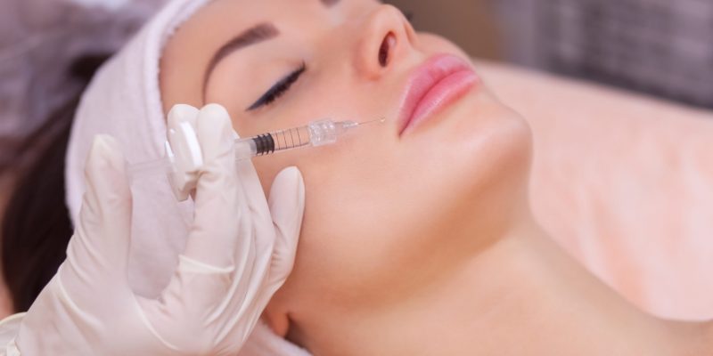The doctor cosmetologist makes the Botulinotoxin injection procedure for tightening and smoothing wrinkles on the face skin of a beautiful, young woman in a beauty salon.Cosmetology skin care.