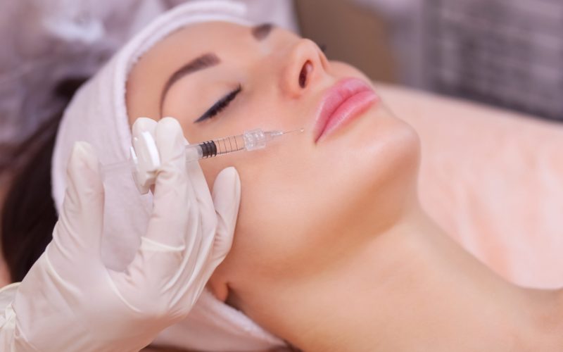 The doctor cosmetologist makes the Botulinotoxin injection procedure for tightening and smoothing wrinkles on the face skin of a beautiful, young woman in a beauty salon.Cosmetology skin care.