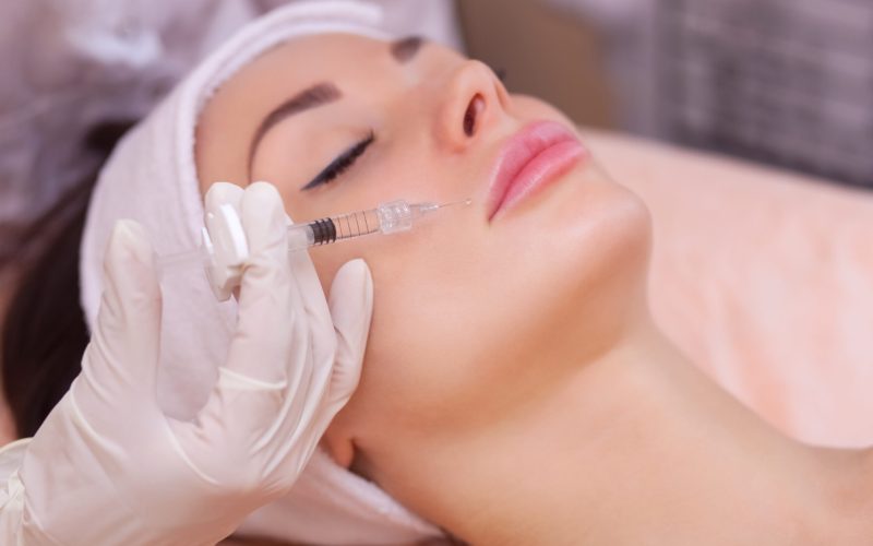 The doctor cosmetologist makes the Botulinotoxin injection procedure for tightening and smoothing wrinkles on the face skin of a beautiful, young woman in a beauty salon.Cosmetology skin care.