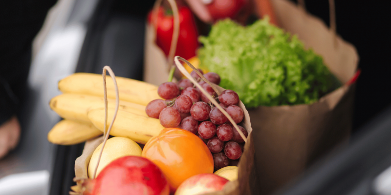 Verdure colorate, spezie come curcuma, zenzero e cannella, e frutta antiossidante come mirtilli e melograno disposte artisticamente su sfondo in legno.