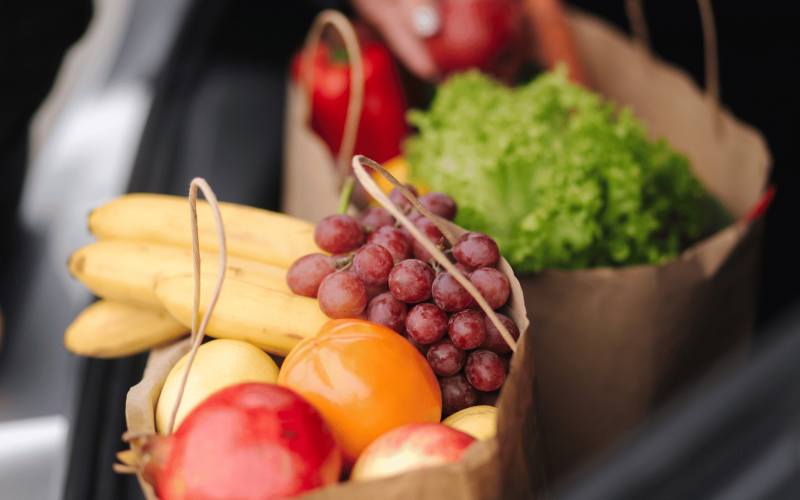 Verdure colorate, spezie come curcuma, zenzero e cannella, e frutta antiossidante come mirtilli e melograno disposte artisticamente su sfondo in legno.
